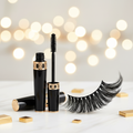 Luxury mascara wand and tube in black and gold packaging with dramatically long voluminous lashes on white marble surface