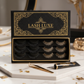 Luxurious foam mink false eyelashes in elegant black and gold packaging box with tweezers on white marble surface