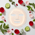 Luxury facial sheet mask surrounded by fresh cucumber slices and rose petals on white background